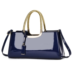 Détail du sac polochon en cuir verni bleu marine avec poignée tissée dorée et bandoulière