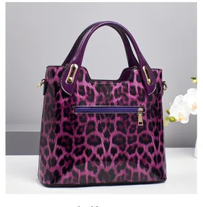 Detailed view of the shiny purple leopard print handbag with gold zipper and dual handles