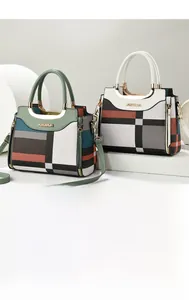 Detail of color-block plaid handbag featuring golden metal handles and geometric design