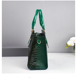 Detail view of emerald green embossed faux leather handbag with gold metal D-rings