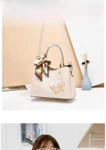 Detail of cream PU leather handbag featuring floral embroidery and decorative silk handle scarf