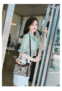 Detail of vintage floral jacquard handbag with black leather trim and golden hardware