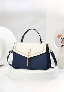 Detail view of contrast leather handbag with pearl cat-ear buckle and metal tassels
