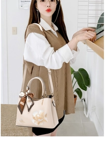 Detail of floral embroidery and printed silk scarf on a beige shoulder bag