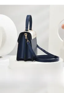 Side view of multi-compartment accordion handbag with contrast leather panels and gold hardware