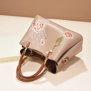 Sac à main élégant en cuir tan avec broderies florales et pendentif feuille dorée
