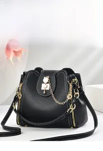 Detail of black bucket bag with lychee texture, golden chain and white pearl accents