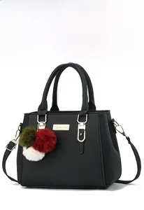 Macro shot of black litchi grain leather handbag with gold metal logo and colorful pompom