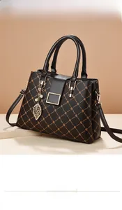 Détail du sac cabas marron avec imprimé monogramme trèfle et breloque perle dorée