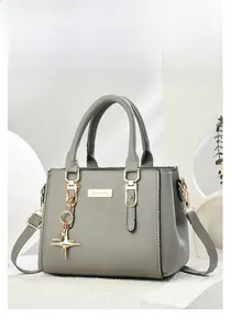 Close-up of grey leather tote with gold hardware and star charm on geometric stand