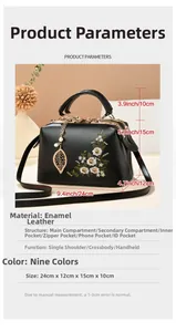 Detail of black patent leather handbag with floral embroidery and gold chain charm