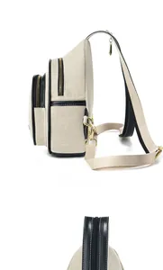 Detail view of beige canvas backpack featuring black leather trim and multi-zipper layers