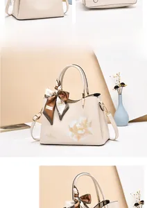Detail of floral embroidery and decorative silk scarf on cream lady shoulder bag