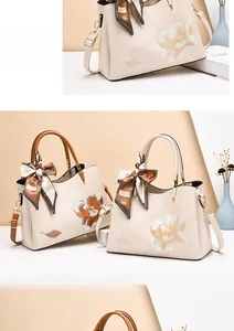 Detailed macro view of embroidered floral patterns on premium cream leather handbags