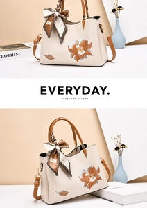 Detail of elegant cream faux leather handbag featuring floral embroidery and silk scarf