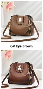 Detail of cat's eye brown leather bucket bag with pearl lock and gold hardware