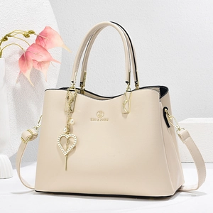 Elegant cream leather tote bag for women featuring a gold heart pearl pendant and top handles