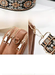 Detail of golden metal zippers and ethnic style woven strap on brown leather crossbody bag
