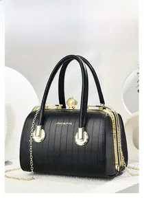 Detail of black textured handbag with golden frame clasp, pearl, and chain strap