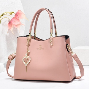 Elegant pink women's handbag with gold hardware and heart pearl charm in studio setting