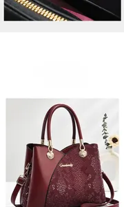 Detail of wine red tote with snake-pattern texture, golden logo, and elegant hardware