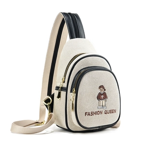 Cream canvas sling bag with bear embroidery and black trim in a side profile view