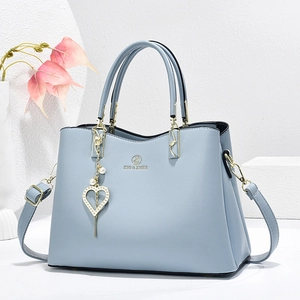 Elegant light blue faux leather tote bag with gold hardware and heart pearl charm