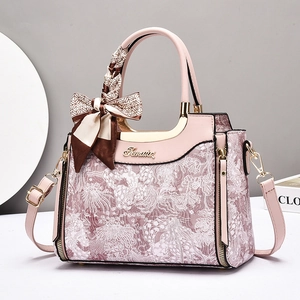 Elegant pink floral handbag with gold hardware and a decorative silk scarf on the handle
