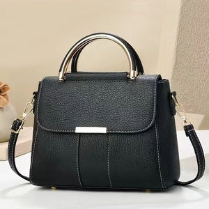Détail d'un sac à main en cuir noir avec poignées rondes dorées et coutures verticales