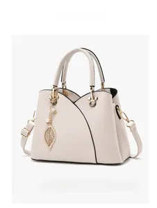 Detailed side view of off-white lychee grain handbag with golden leaf pendant and strap