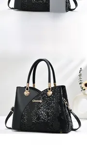 Detail of black crossbody bag with faux snake skin texture and gold lion head hardware