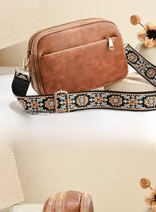 Detail of vintage brown crossbody bag with bohemian embroidered strap and triple zipper