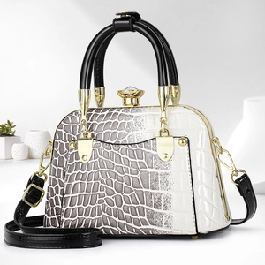 Detail of white crocodile texture bag with gold gemstone clasp and glossy black handles