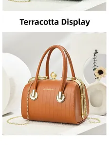 Detail of ochre PU leather handbag featuring pearl clasp and fine vertical embossing