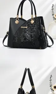 Detail view of black handbag featuring snake-embossed leather and gold Ganhanly logo