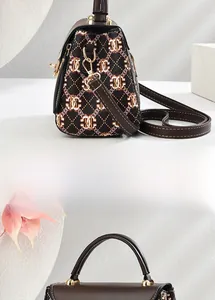 Detail view of brown leather bag showing interlocking print fabric and gold metal buckle