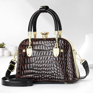 Detail of brown crocodile pattern shell bag with gold hardware and black handle