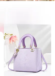Detail of purple embossed leather handbag with snake texture and gold metal hardware
