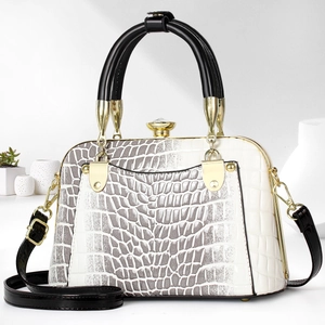 Close-up of a two-tone crocodile textured shell bag with gold hardware and top handles