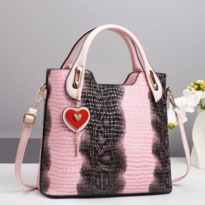 Detail of pink and brown crocodile texture handbag with heart charm and gold hardware