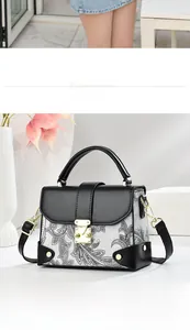 Detail of black and white paisley pattern handbag with golden buckle and leather strap