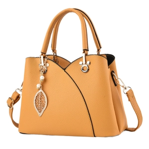 Elegant mustard yellow lychee pattern handbag with dual handles and gold leaf pendant