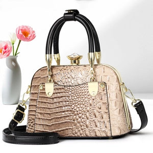 Detail of champagne gold crocodile pattern shell bag with jewel clasp and black handle