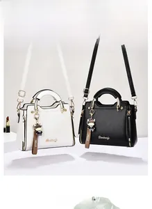 Detail of faux leather crossbody bags in beige and black with cute ox charm and logo