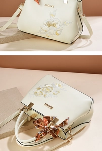 Detailed embroidery on off-white handbag with gold logo and floral patterns