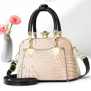 Detail of elegant crocodile-patterned shell bag with a crystal clasp and pink tulips