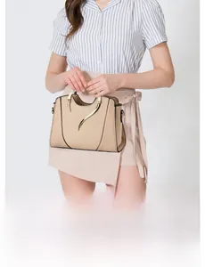 Detail view of beige leather handbag with gold curved hardware and spacious inner pockets