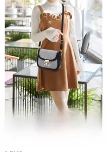 Chic black and white tweed crossbody bag with a round gold swivel lock on a model