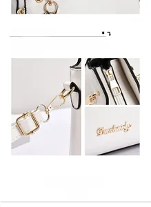 Detailed macro view of gold-plated metal hardware and logo on a white leather handbag