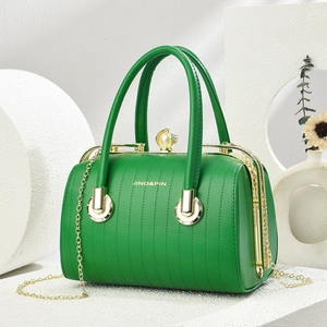 Détail du sac Boston en cuir vert avec fermoir perle, chaîne dorée et texture gaufrée